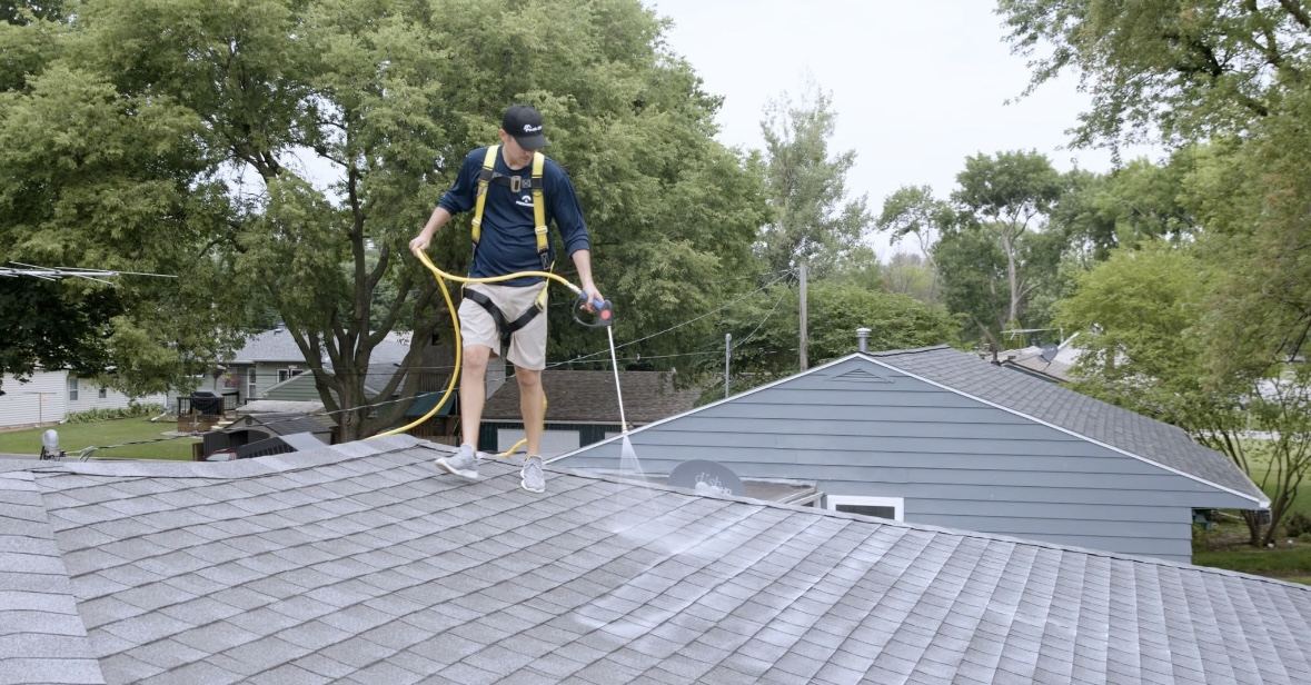 Technician applying plant-based roof restoration treatment to a Utah shingle roof