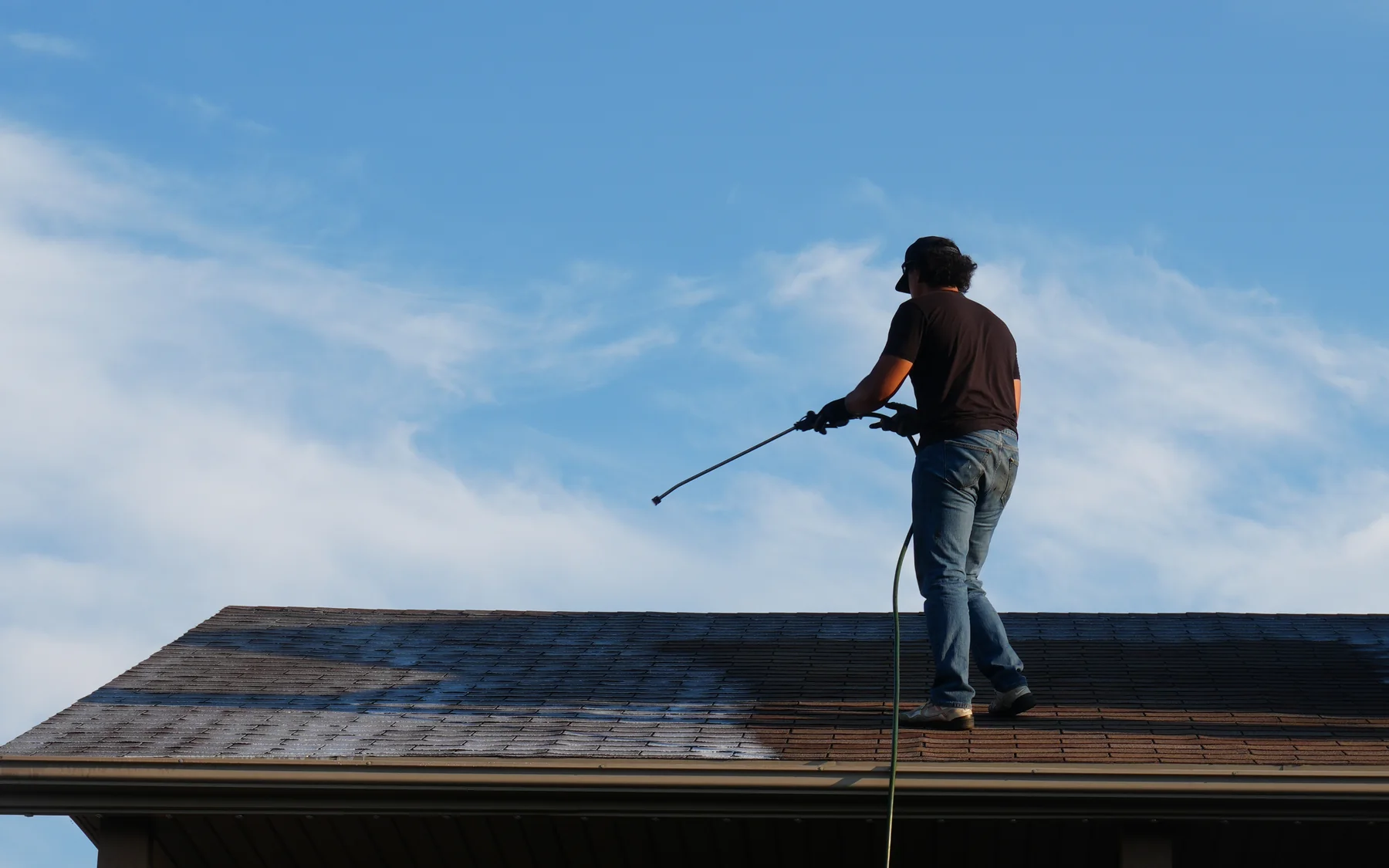 Revive Your Roof technician applying roof rejuvenation treatment evenly across an asphalt shingle slope
