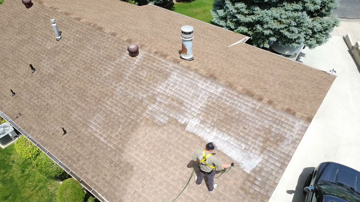 Close drone view of a Revive Your Roof technician treating asphalt shingles