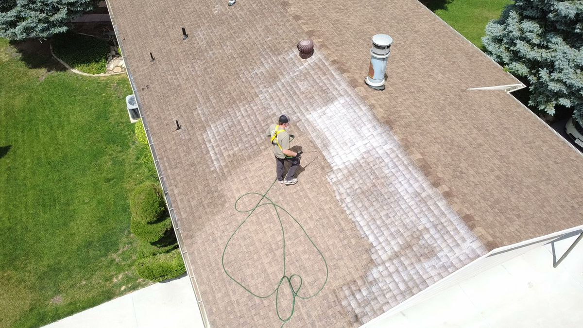 Revive Your Roof technician seen from above while treating a roof slope, on a Wasatch Front home in Utah