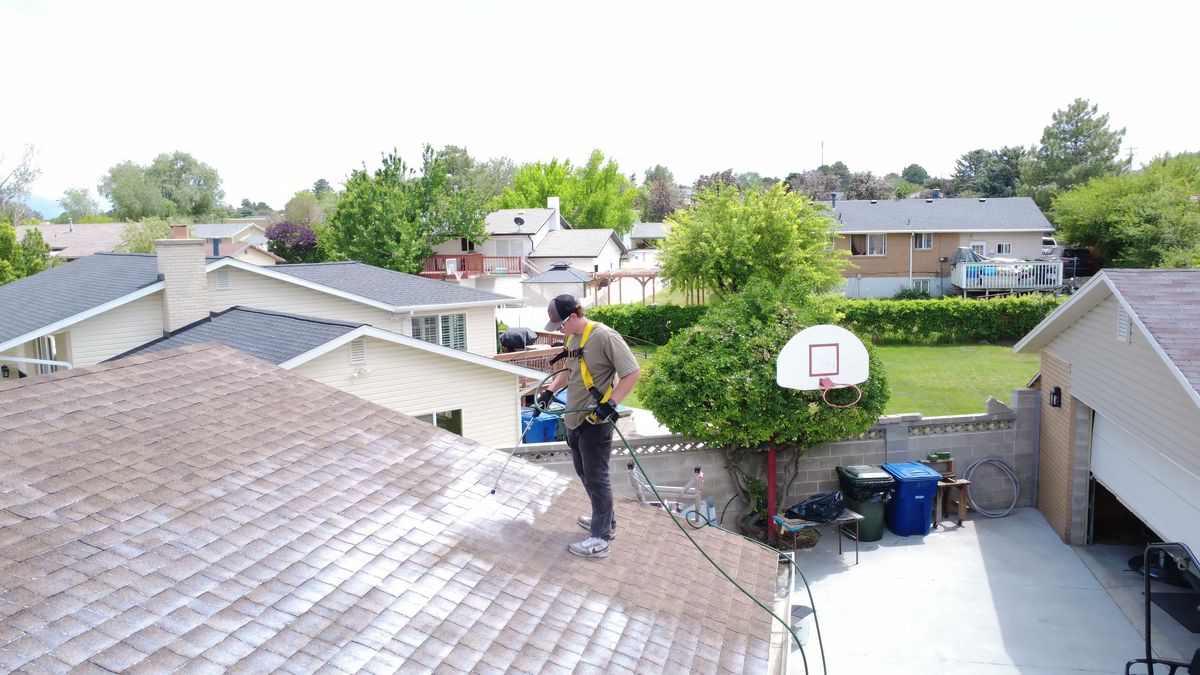 Revive Your Roof technician standing on a Utah roof mid-treatment, on a Wasatch Front home in Utah