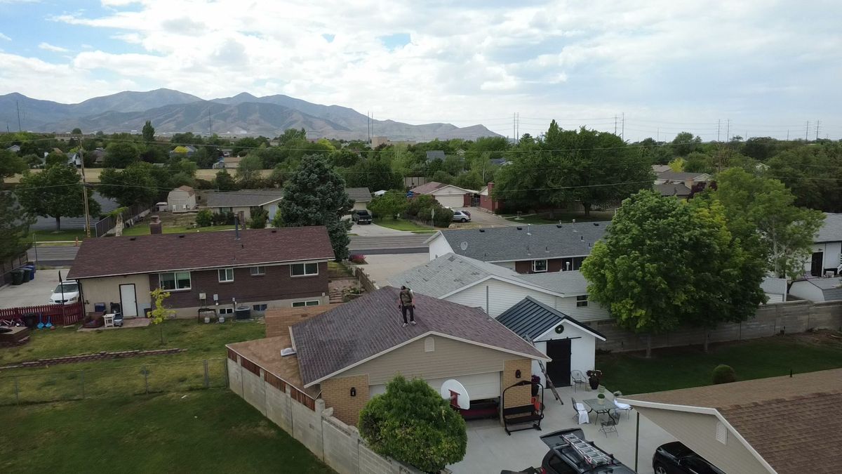 Aerial view of a Utah County neighborhood with mature trees and the Wasatch range in the distance