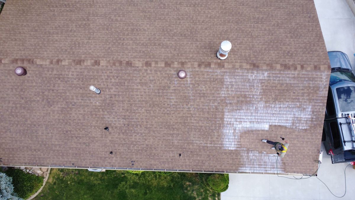 Drone view of a Utah roof mid-treatment, the darker treated section clearly separated from the dry untreated shingles